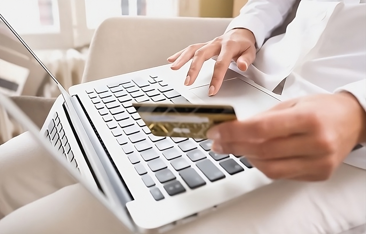 Image of woman holding a credit card in front of a laptop